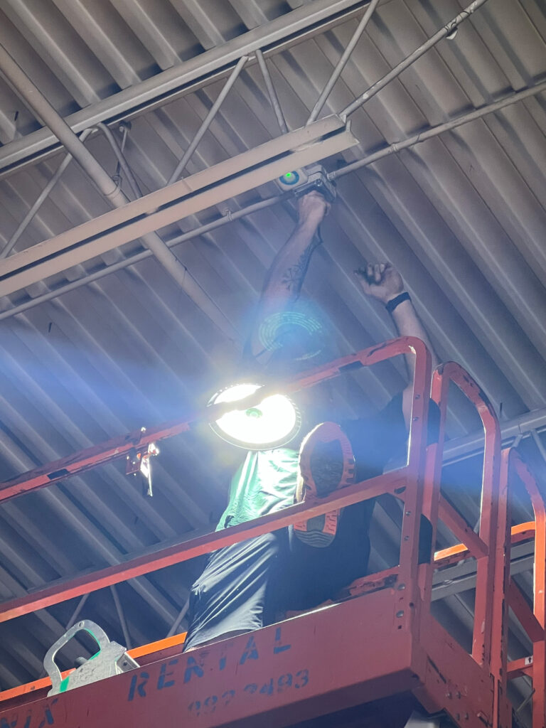Commercial electrician installing LED High Bay Fixture in manufacturing facility.